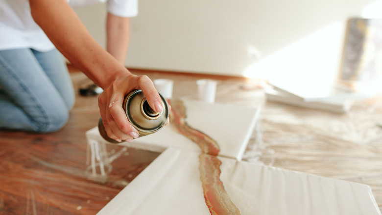 person spraying paint onto white canvas