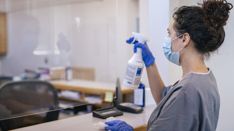 person cleaning plexiglass divider