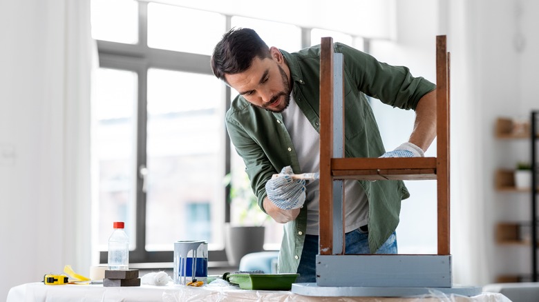 Man in gloves finishing furniture