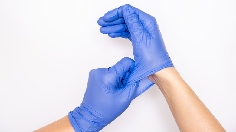 Medical professional donning nitrile gloves