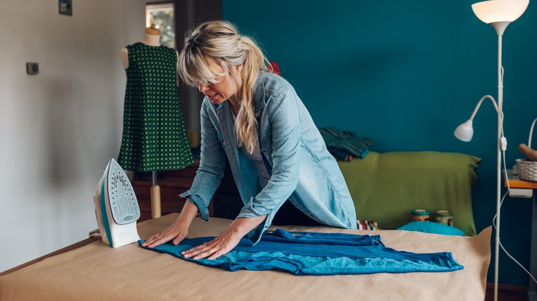 Woman ironing wrinkled blue shirt