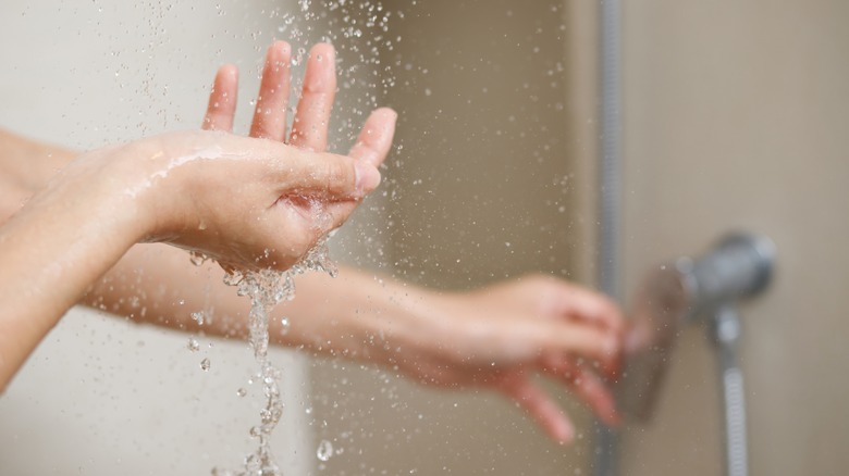 Woman checking shower temperature