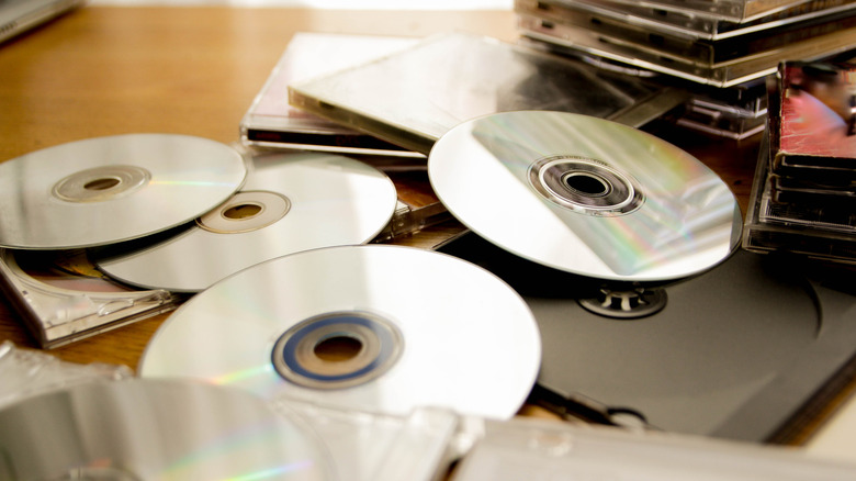 Stacks of CDs with and without cases rest on a table