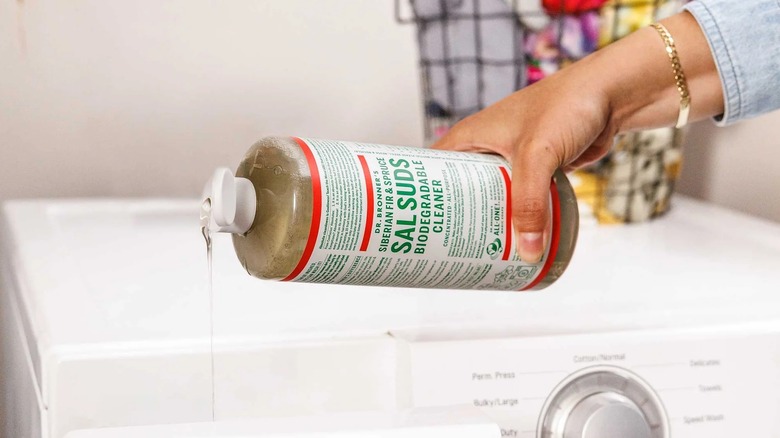 Person pours Dr. Bronner's Sal Suds in laundry room