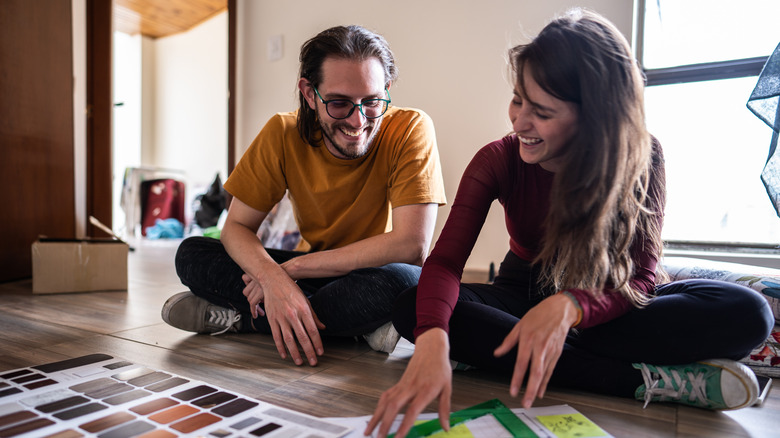 A couple sits on the floor, trying to make décor decisions.