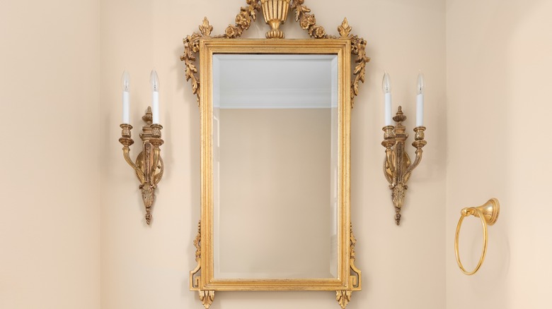 gold mirror flanked by gold wall sconces