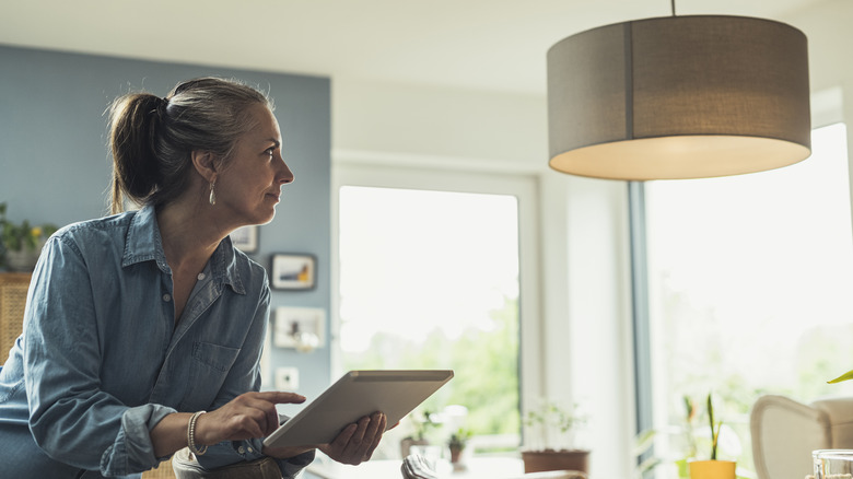 Woman operating lighting fixture with tablet