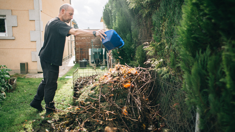 Man pouring items onto compost pile