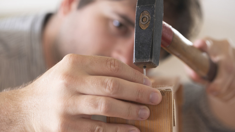 A man is focusing on hammering a nail