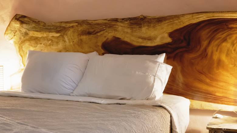 A large slab of wood is used as a headboard behind pillows