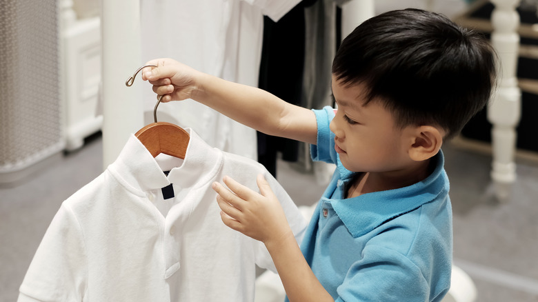 boy holding white shirt on hanger