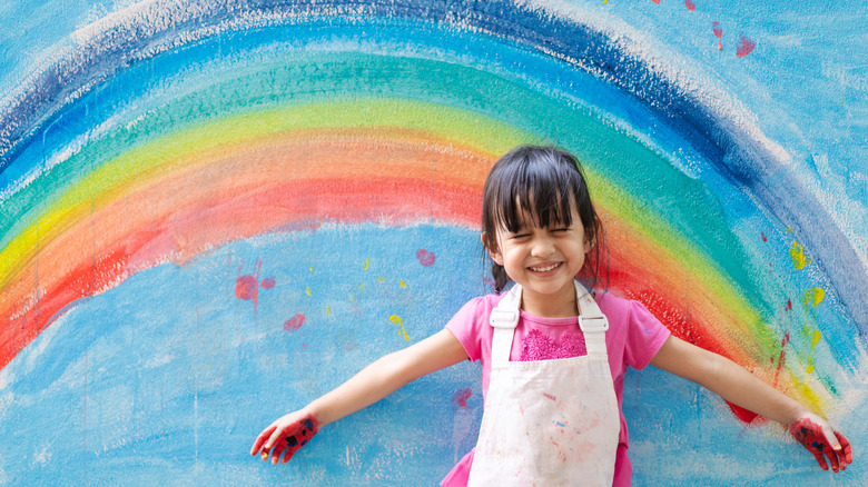 girl standing by rainbow painting