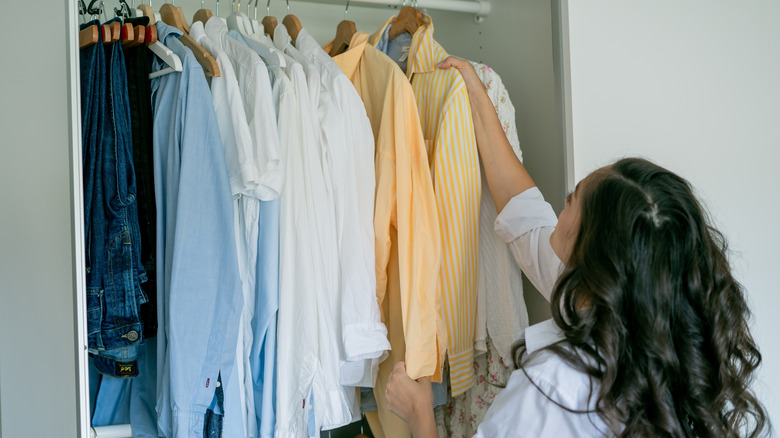 A woman hangs up clothes in a closet