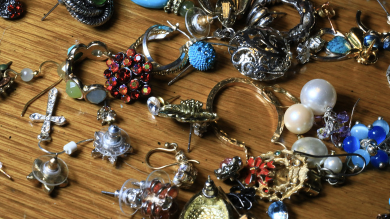 Pile of mismatched earrings and rings on wooden countertop