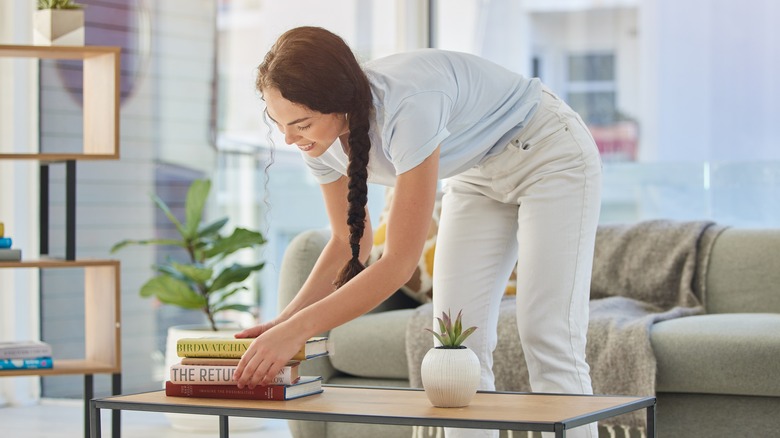 Woman styling books on a wooden coffee table