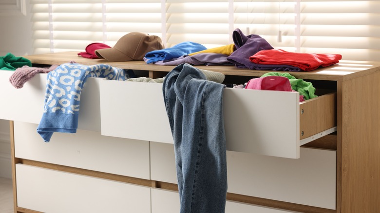 White dresser with colorful clothes spilling out of drawers