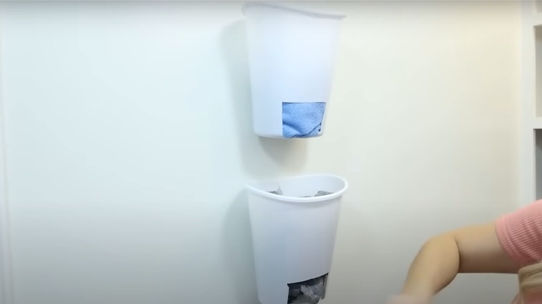 White Dollar Tree waste baskets with rectangular holes hanging on wall