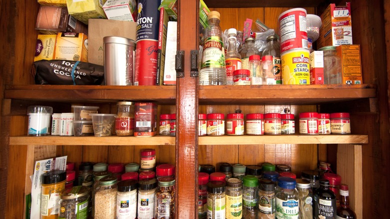 Wood cabinet full of spice jars and cooking supplies