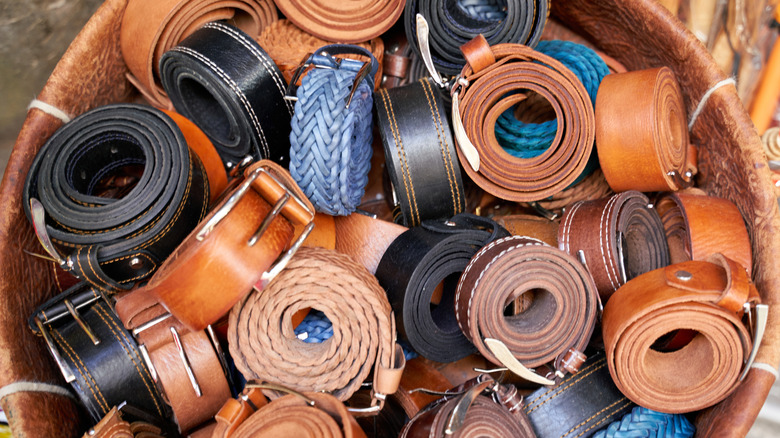 Many rolled leather belts in brown and black