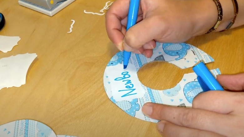 A woman writing newborn in blue marker on DIY closet divider