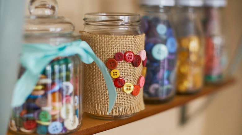 A shelf with crafting buttons in bottles.