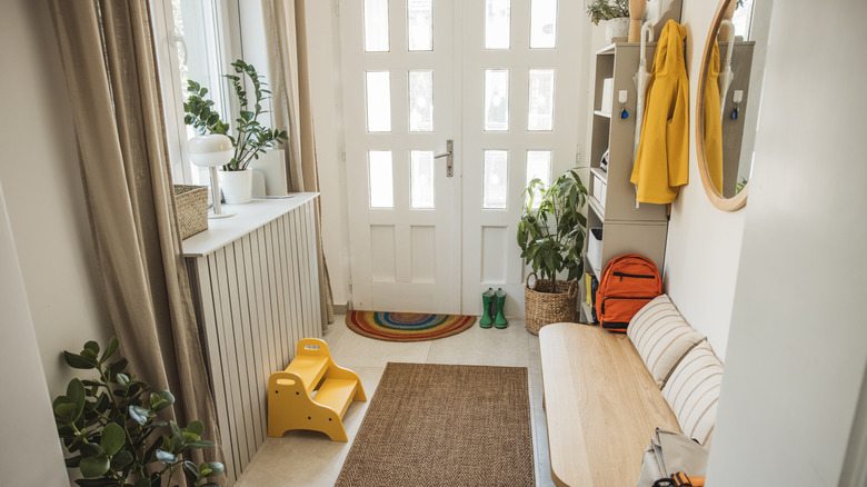 Front entryway of a family home with shelves, storage boxes, a console table, and a small bench.