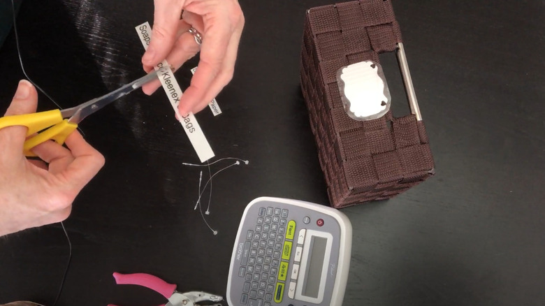 A person cutting labels for tags to attach to a wall basket.