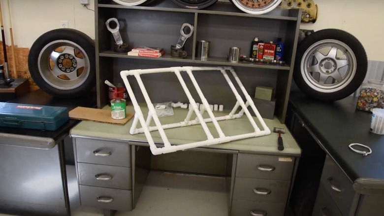 DIY PVC three-slot bike rack sitting on garage workbench