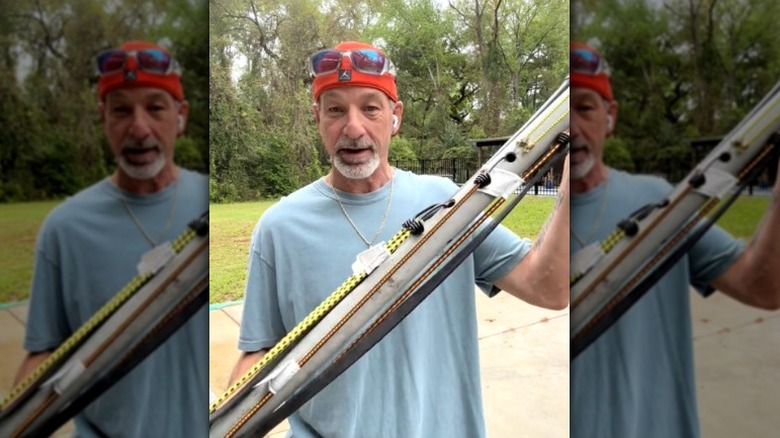 man holding PVC pipe with bungee cords stored on it