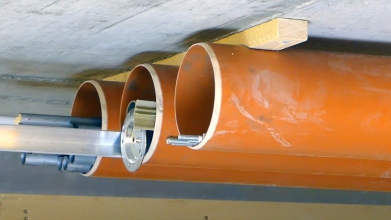 orange ceiling-mounted PVC pipes holding metal pipes and angle bar