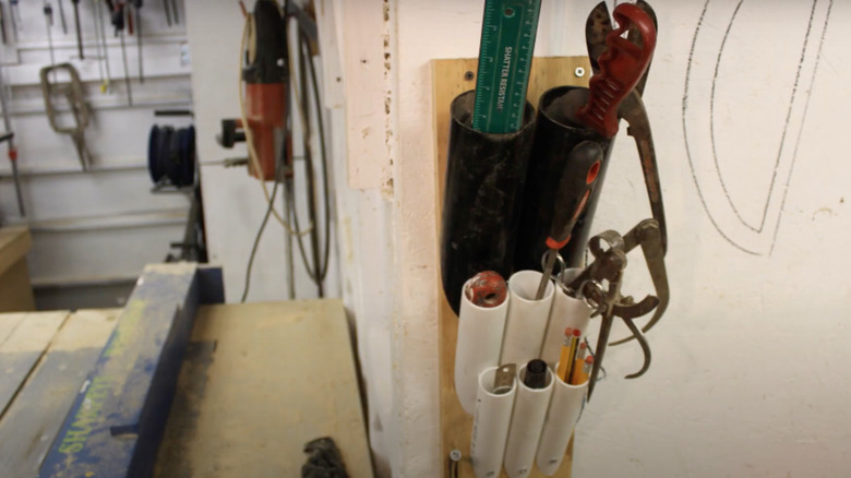 DIY PVC storage slots holding small tools in garage workshop