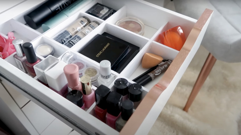 An IKEA ALEX drawer opened to show a drawer divider organizing various beauty products