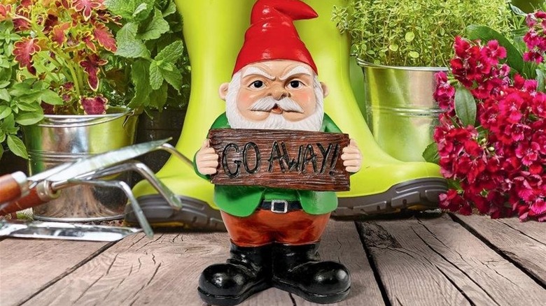 gnome statue with "go away" sign