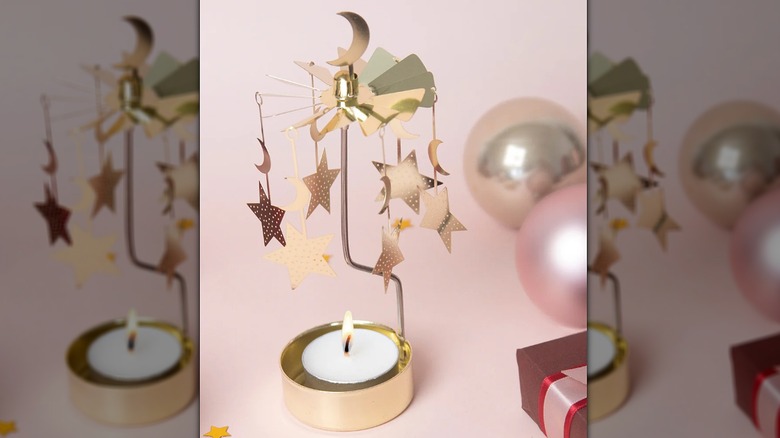 Gold rotating candle holder with stars and a moon with a pink background