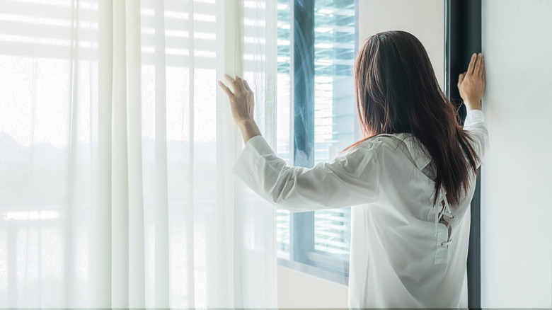 woman opening window blinds