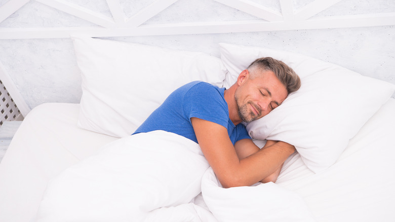 man sleeping in white bedroom