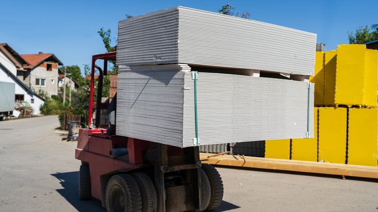 forklift carrying a stack of drywall