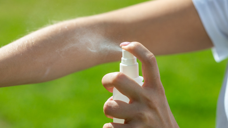 person spraying repellent on arm