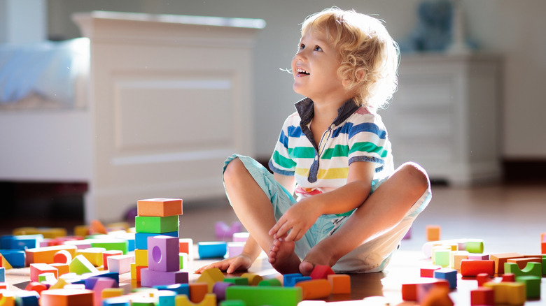 A young boy sits in a pile full of messy blocks