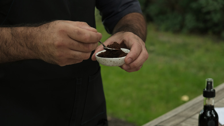 person scooping coffee grounds yard