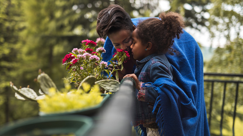 mother and daughter smelling flowers