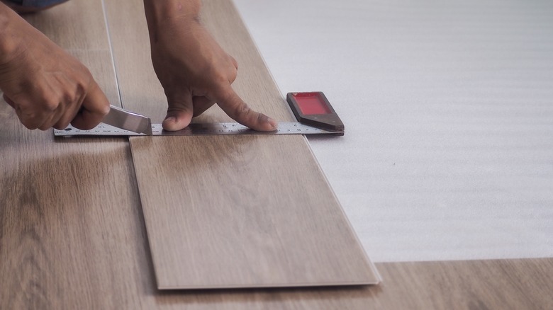 person cutting vinyl plank flooring