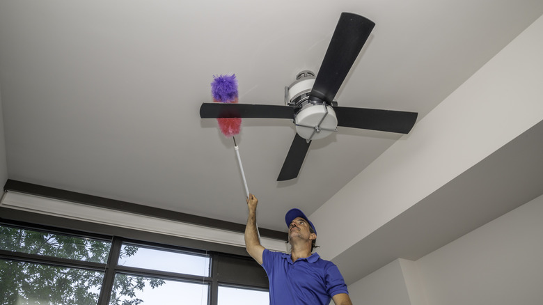 Person dusting ceiling fan