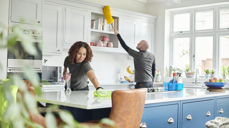 man dusting kitchen cabinets