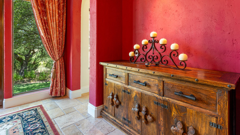 Rust red entryway with ornate rug and antique sideboard