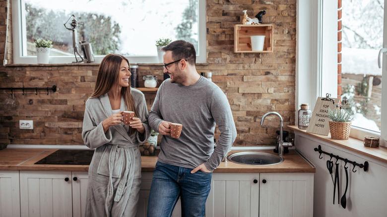 couple standing in front of faux stone wall in kitchen