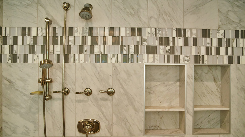 Band of mosaic tile across shower wall with brass fixtures