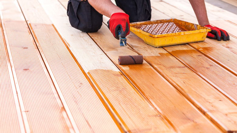 person using roller staining deck