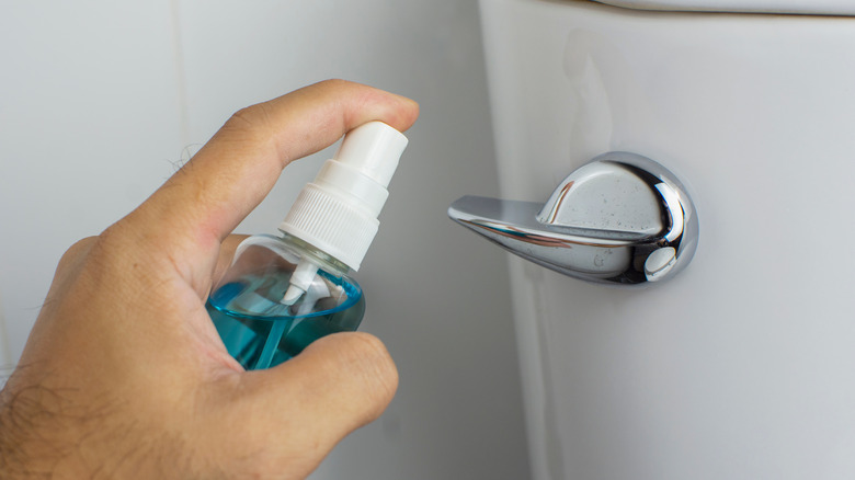 Cleaning toilet handle with disinfectant spray