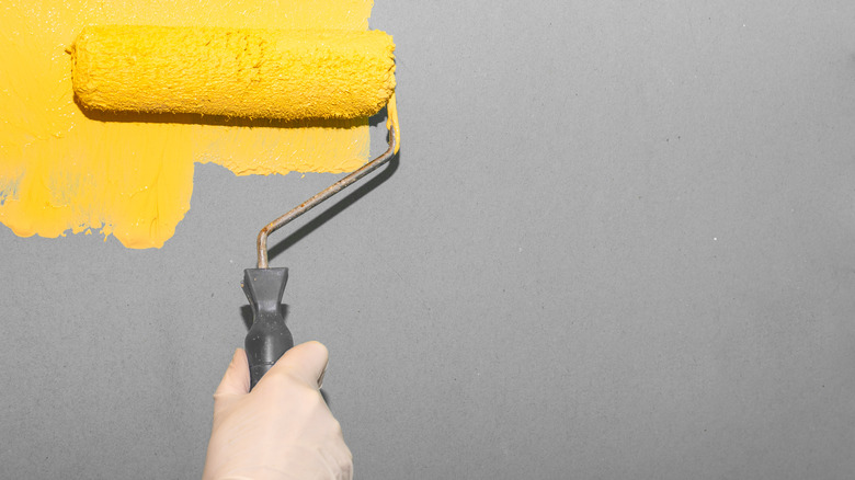 Woman paints gray surface yellow